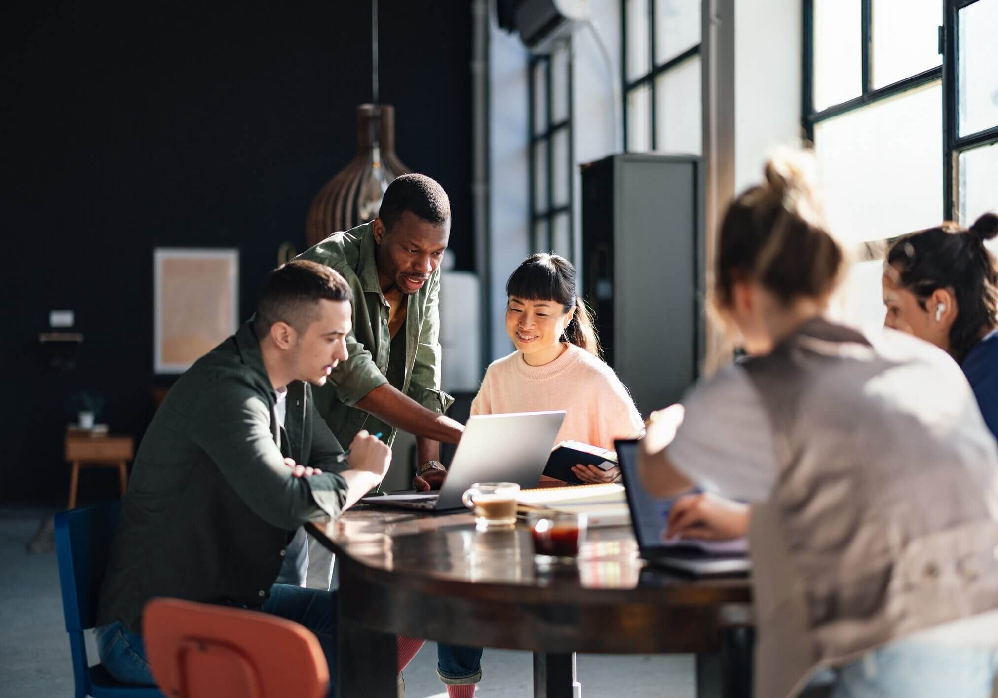 Young professionals or students collaborating in a bright, contemporary co-working environment, displaying teamwork and productivity.