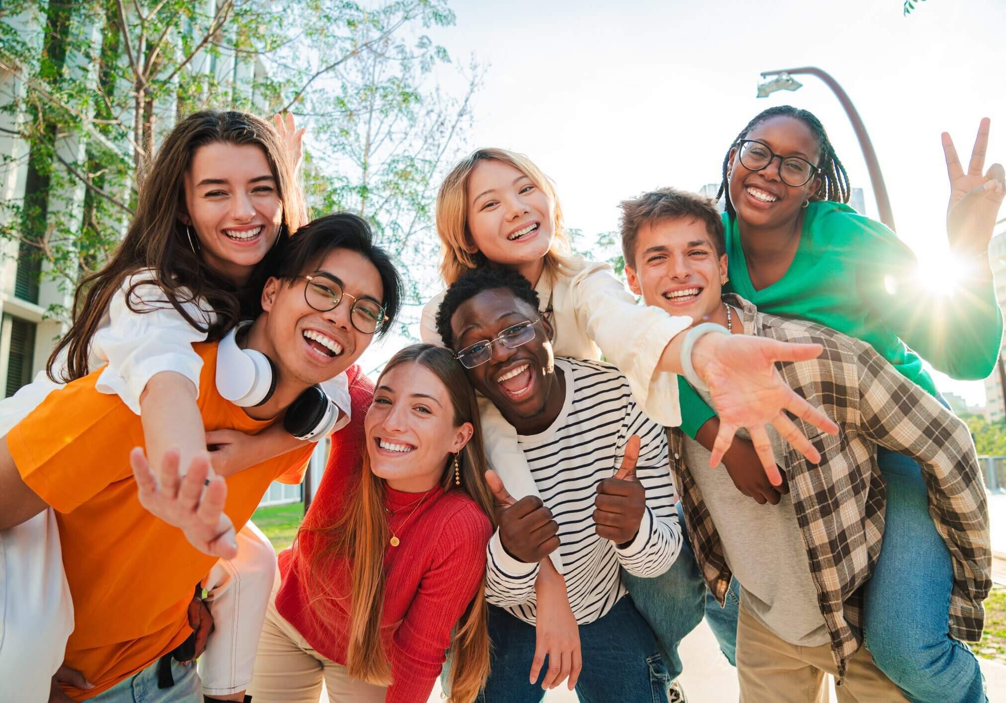 Big group of multiracial young student people smiling, gesturing and looking at camera. Happy internacional teenagers laughing. Cheerful friends enjoying their freedom. Classmates on friendly meeting. High quality photo